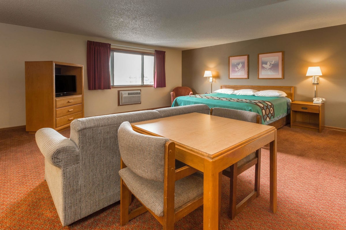 A hotel room with a bed, a desk, a chair, a television, and a window with curtains.