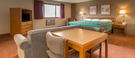 A hotel room with a bed, a desk, a chair, a television, and a window with curtains.