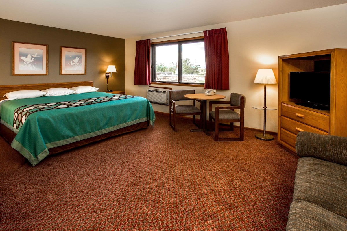 A hotel room with a bed, a desk, a chair, a television, and a sofa.