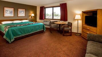 A hotel room with a bed, a desk, a chair, a television, and a sofa.