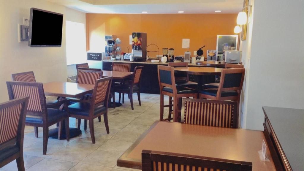 A restaurant with multiple tables and chairs, a counter with a cash register, and a television mounted on the wall.