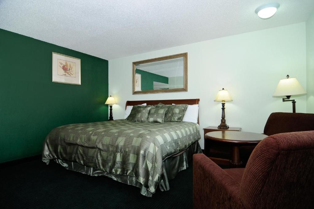 A hotel room with a bed, two bedside tables, a chair, and a mirror on the wall.