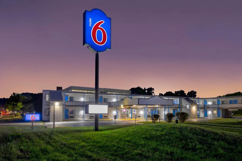 Un motel con un llamativo letrero con el número '6', un edificio moderno con varias unidades y una entrada bien iluminada.