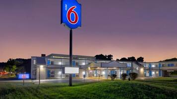 Un motel con un llamativo letrero con el número '6', un edificio moderno con varias unidades y una entrada bien iluminada.