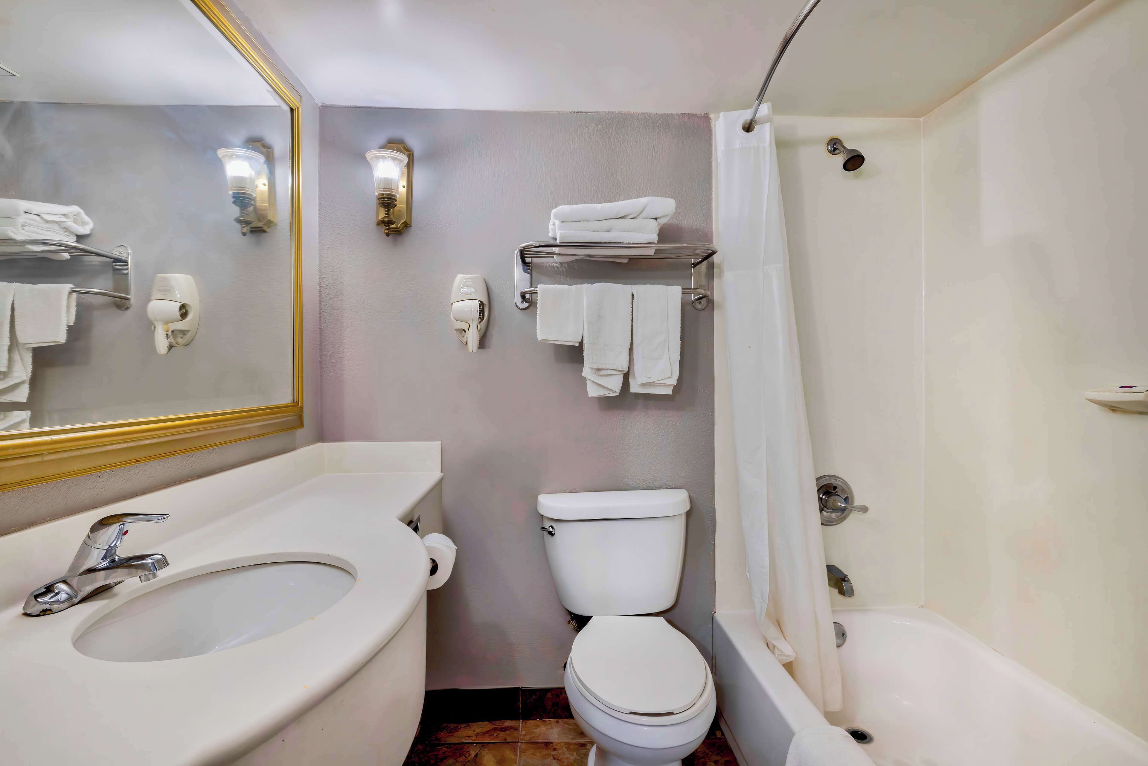 Un bagno con lavandino, WC e vasca. Asciugamani su un portascopevoli e una tenda da doccia.