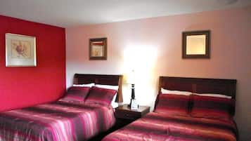 A hotel room with two beds, a nightstand, and a wall-mounted lamp.