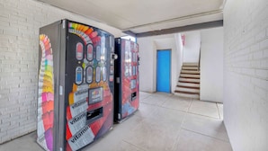 Two vending machines with colorful designs in a hallway with white brick walls and a blue door. - Motel 6 - Harrisburg, PA - Near PA Expo Center  (Harrisburg)