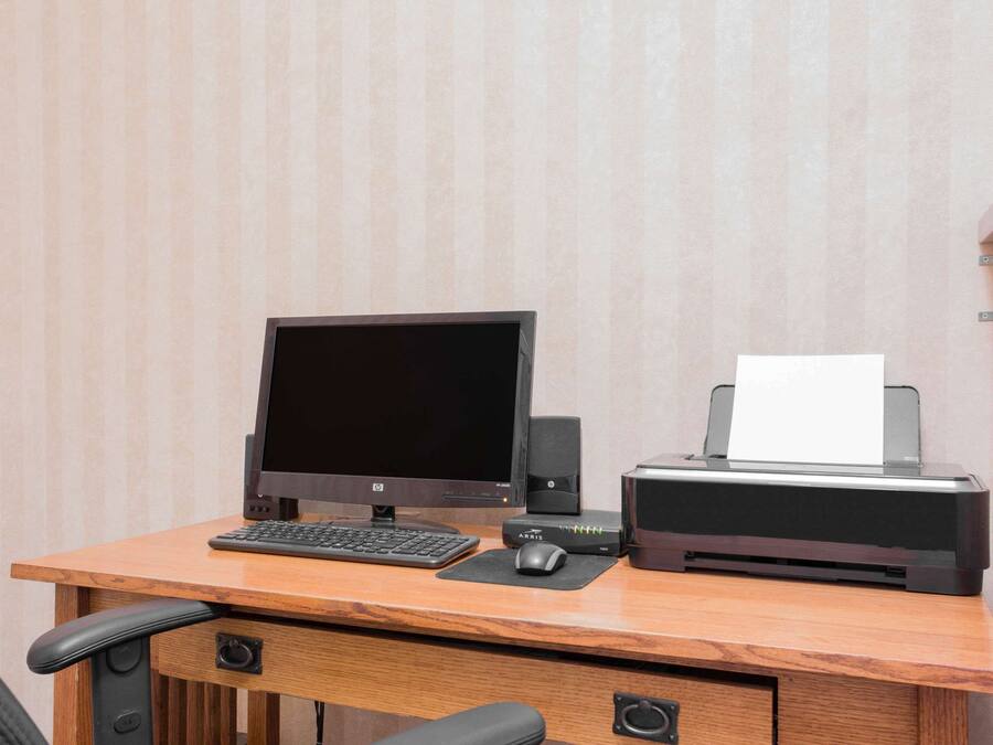 Un escritorio de madera con un monitor de computadora, teclado, ratón e impresora.