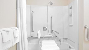A white, accessible shower area with a grab bar, a handheld showerhead, and a seat. - Super 8 by Wyndham Havre (Havre)