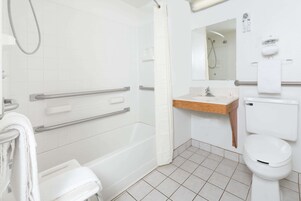 A modern bathroom with a shower, toilet, and sink. It includes grab bars and a towel rack.
