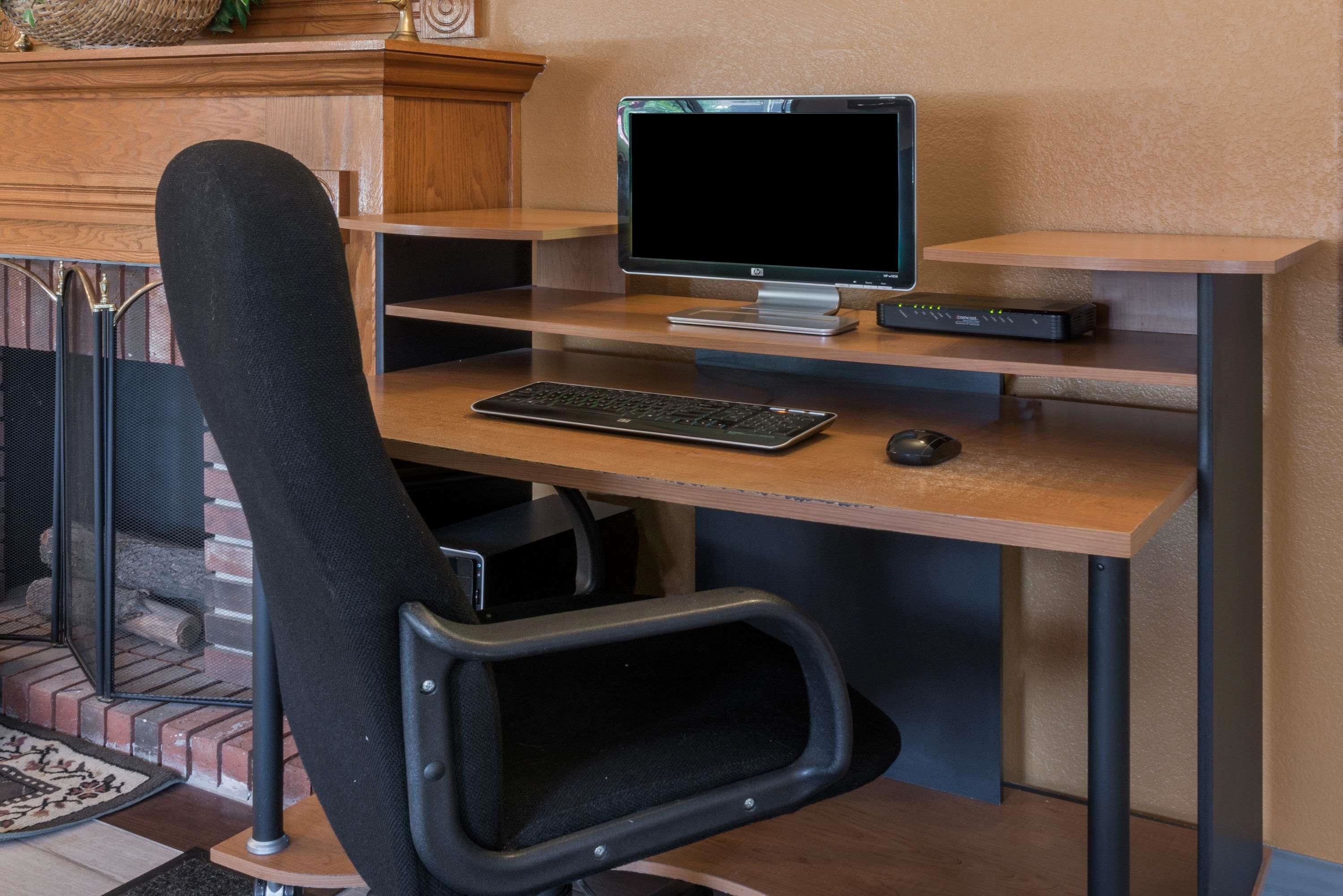 Postazione da lavoro a casa con computer, tastiera e mouse su una scrivania in legno.