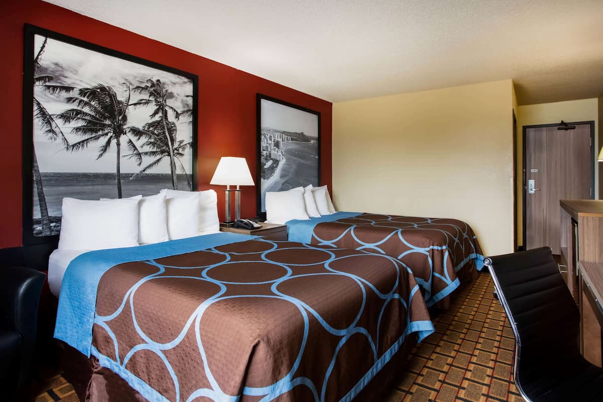 Une chambre d’hôtel avec deux lits, un bureau et une chaise.