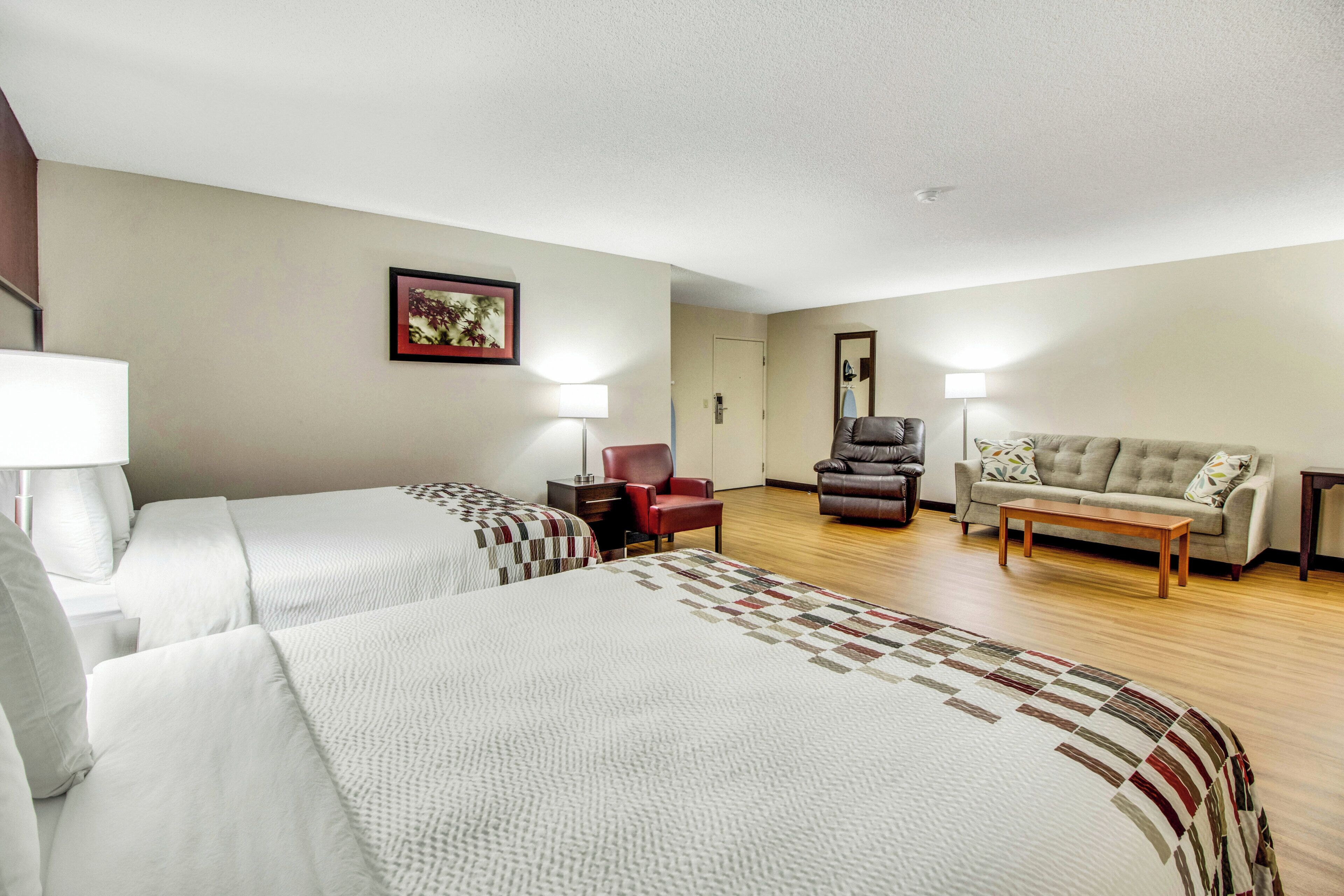 A hotel room with two beds, a sofa, a chair, and a desk.