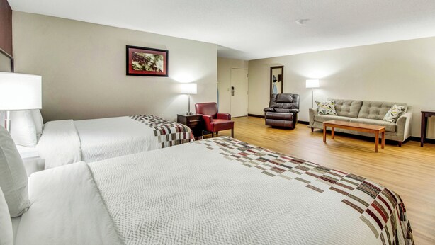 A hotel room with two beds, a sofa, a chair, and a desk. - Red Roof Inn Franklin, KY (Franklin)