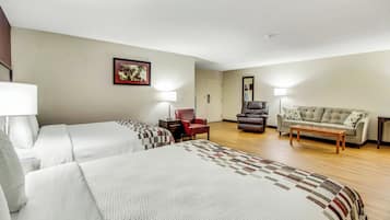 A hotel room with two beds, a sofa, a chair, and a desk.