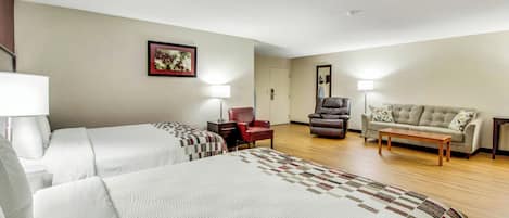 A hotel room with two beds, a sofa, a chair, and a desk.