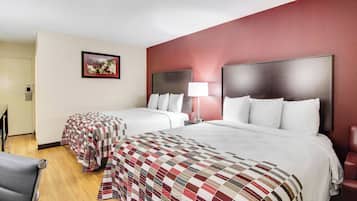 Habitación de hotel con dos camas, un escritorio, una silla, una lámpara y un cuadro en la pared.
