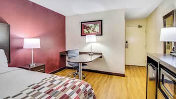 Una habitación de hotel con cama, escritorio, silla y puerta.