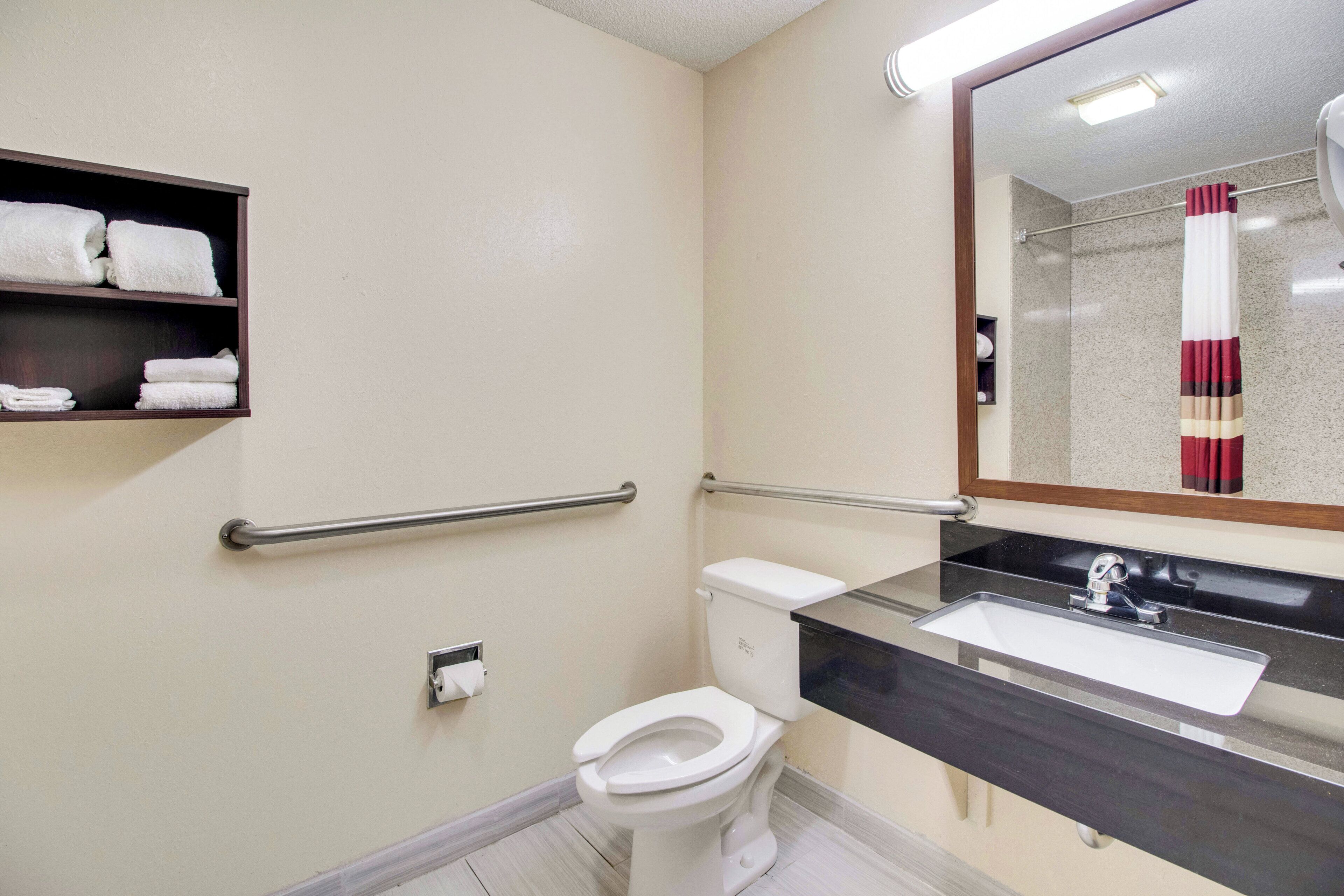 Un baño con inodoro, lavamanos y espejo.