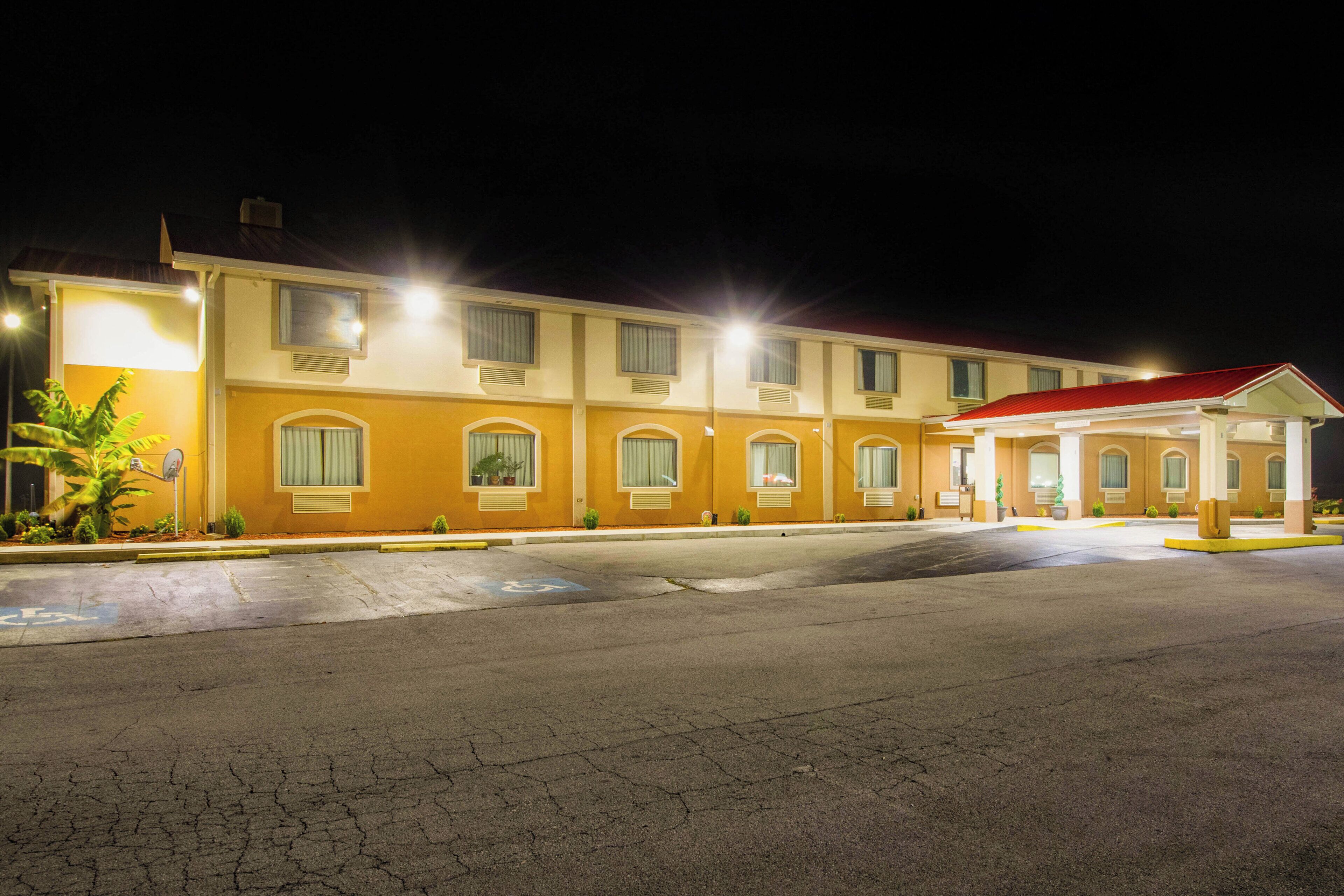 A multi-story hotel with a red-roofed entrance and a parking lot.