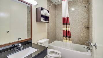 A bathroom with a sink, toilet, bathtub, and a shower curtain.