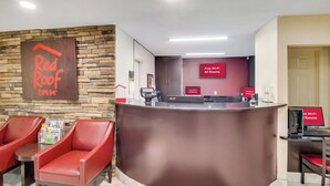 A reception desk with a stone wall backdrop, red chairs, and a sign indicating free Wi-Fi in all rooms. - Red Roof Inn Franklin, KY (Franklin)