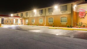 A Red Roof Inn with a parking lot and a building facade featuring multiple windows and a neon sign. - Red Roof Inn Franklin, KY (Franklin)