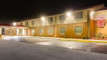 A Red Roof Inn with a parking lot and a building facade featuring multiple windows and a neon sign.