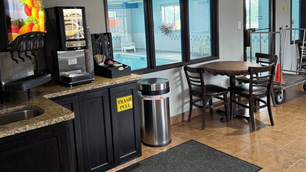 A coffee shop interior with a coffee machine, trash can, and seating area.