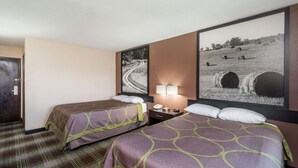 A hotel room with two beds, a nightstand, a lamp, and two large landscape paintings on the walls.