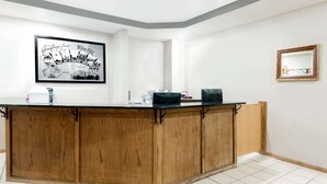 A reception desk with a framed welcome sign, a coffee machine, and a black bag on the counter.