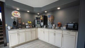 A modern kitchen with white cabinets, a built-in microwave, and a coffee machine.