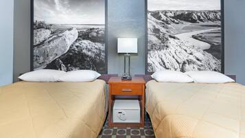 A hotel room with two beds, a nightstand with a lamp, and a safe.