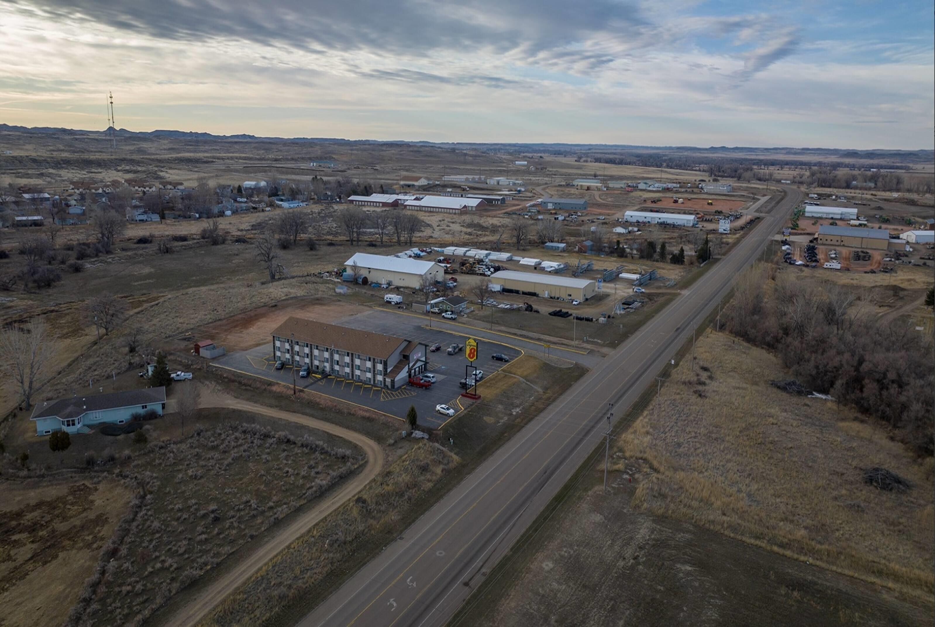 An aerial view of a rural industrial area with multiple buildings, roads, and a clear sky.