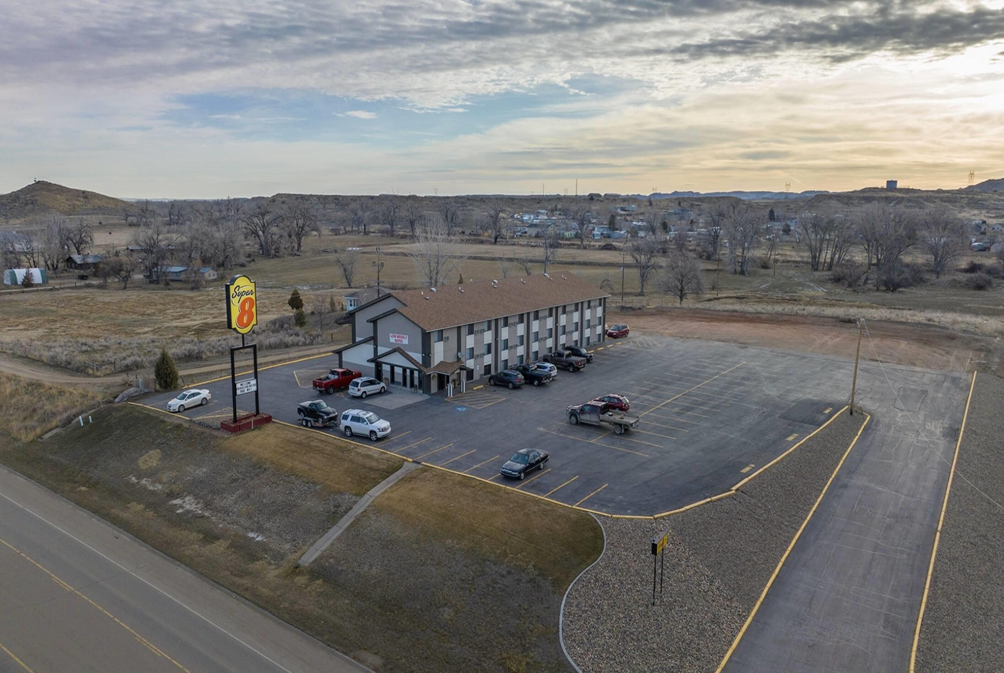 A gas station with multiple fuel pumps, a large building with a sign, and a parking lot with several cars.