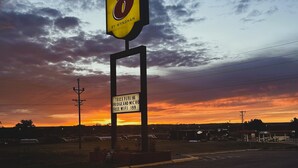 A sign for a business named 'Super 8' by Wyndham, with a sunset in the background.