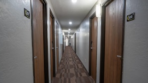 A hotel hallway with carpeted floors, wooden doors, and numbered room signs.