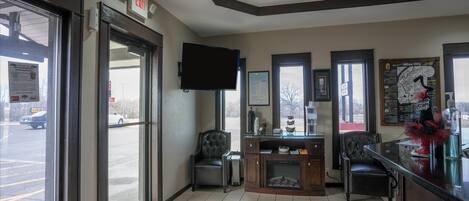A hotel lobby with a reception desk, seating area, and a large window overlooking the street.