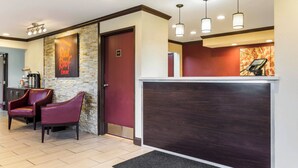 A reception area with a stone wall, a red door, a reception desk, and two leather chairs. - Red Roof Inn Dry Ridge (Dry Ridge)