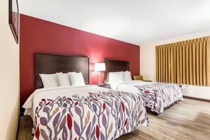 A hotel room with two beds, a red accent wall, a wooden floor, and a window with curtains. - Red Roof Inn Dry Ridge (Dry Ridge)