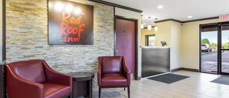 A reception area with a stone wall, two leather chairs, a small table, and an exit sign.