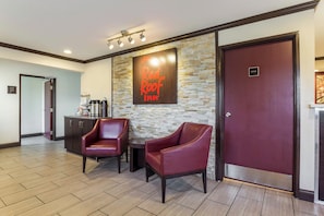 A Red Roof Inn lobby with a stone wall, two leather chairs, a coffee station, and a closed door labeled 'OFFICE'. - Red Roof Inn Dry Ridge (Dry Ridge)