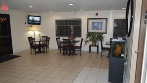 A lobby with a dining area, a television mounted on the wall, a potted plant, and a fish tank. - American Elite Inn (Hazard)