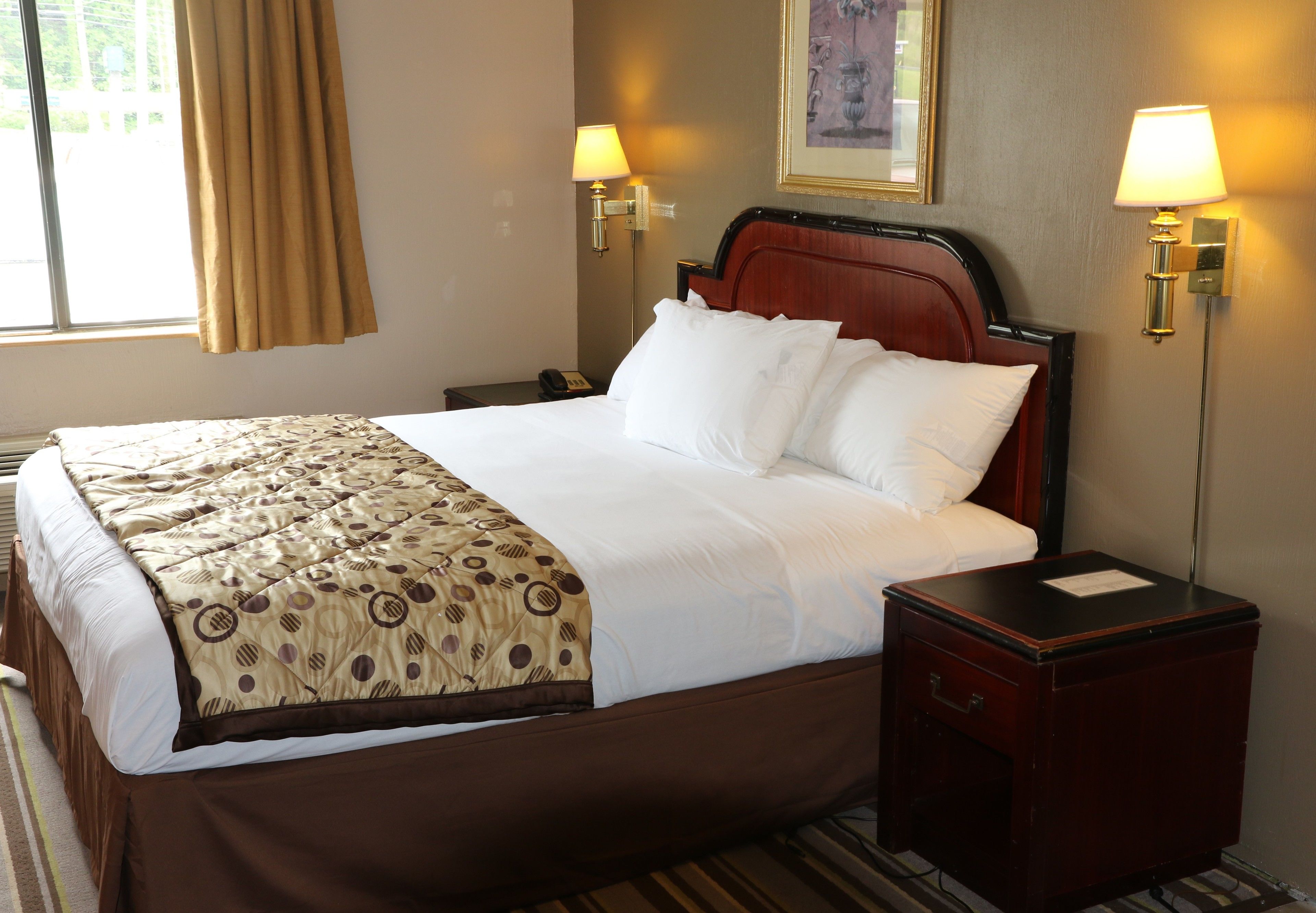 A hotel room with a bed, bedside tables, lamps, and a window with curtains.