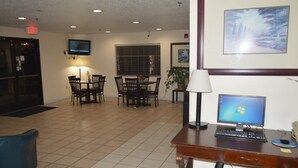 A hotel lobby with a dining area, a desk with a computer, and a TV mounted on the wall. - American Elite Inn (Hazard)