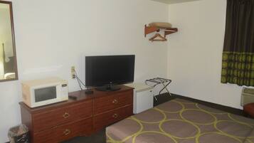 A hotel room with a bed, a television on a dresser, a microwave, a small refrigerator, and a hanging coat rack.