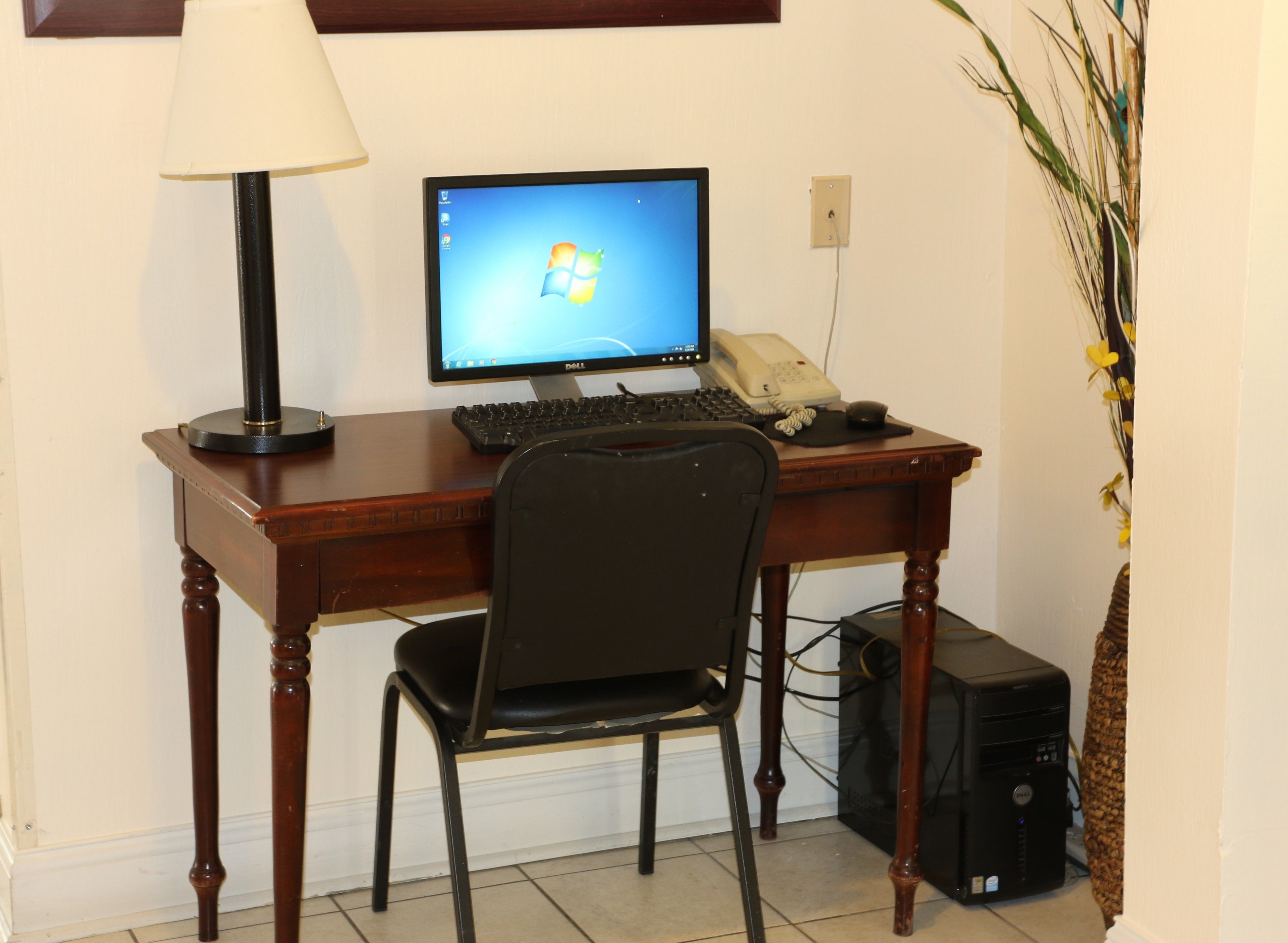 Un escritorio de madera con una computadora, teclado y teléfono.