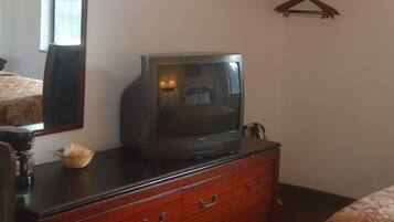 Een hotelkamer met een houten dressoir, een televisie erboven, een spiegel en een wandhouder voor kleding.