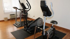 A home gym with three exercise machines, a standing bike, and a treadmill. - American Elite Inn (Hazard)