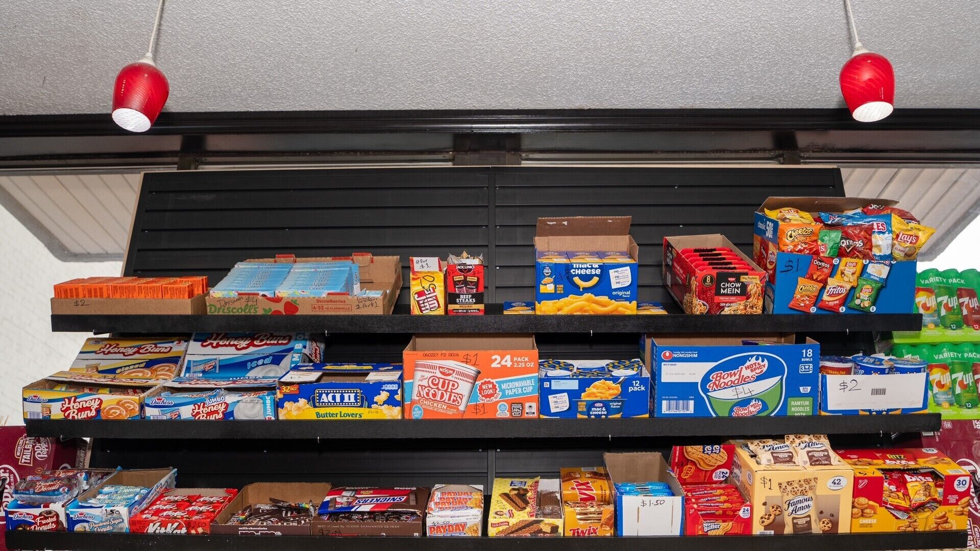 A shelf stocked with various snack items including Honey Buns, popcorn, and boxed snacks.